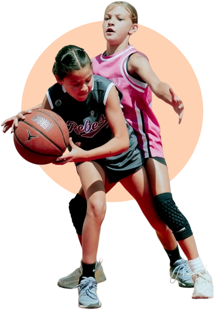 Two young girls playing competitive basketball; one player in a black jersey dribbles the ball while another in a pink jersey defends her, set against a circular orange background.